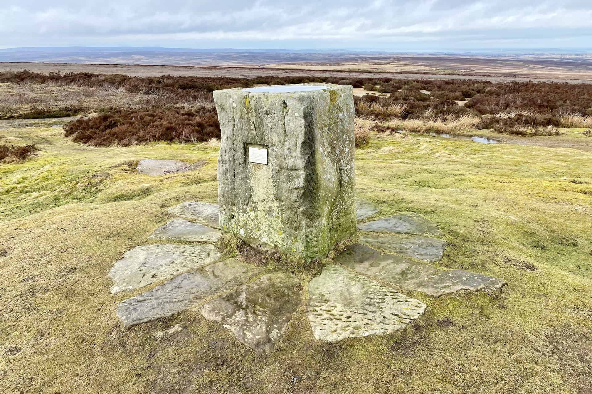 A toposcope stands on the hill on a concrete block near Danby Beacon. Toposcopes are typically found at elevated vantage points, such as hills or summits.