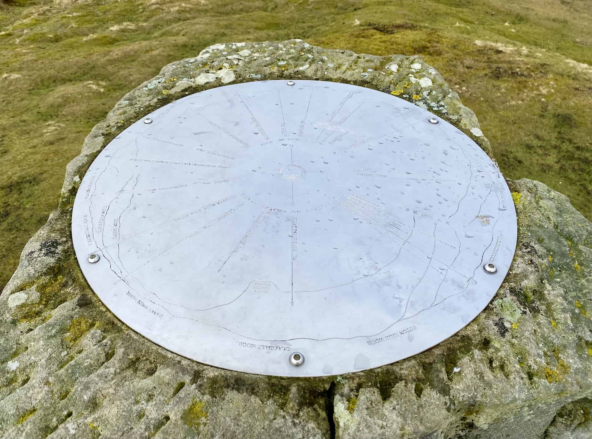 A toposcope stands on the hill on a concrete block near Danby Beacon. Toposcopes are typically found at elevated vantage points, such as hills or summits.