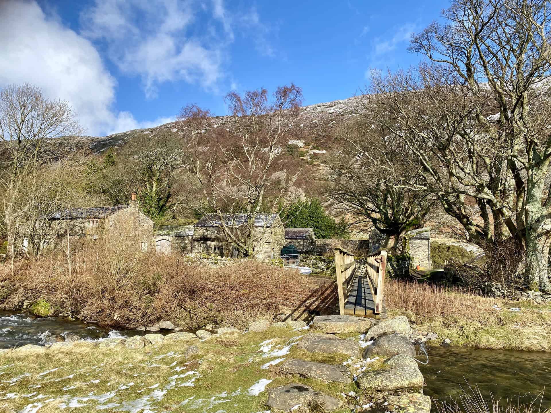 Picturesque farmhouses and farm buildings surrounded by trees at Roundhouse, about one-quarter of the way round this Bowscale Tarn walk.