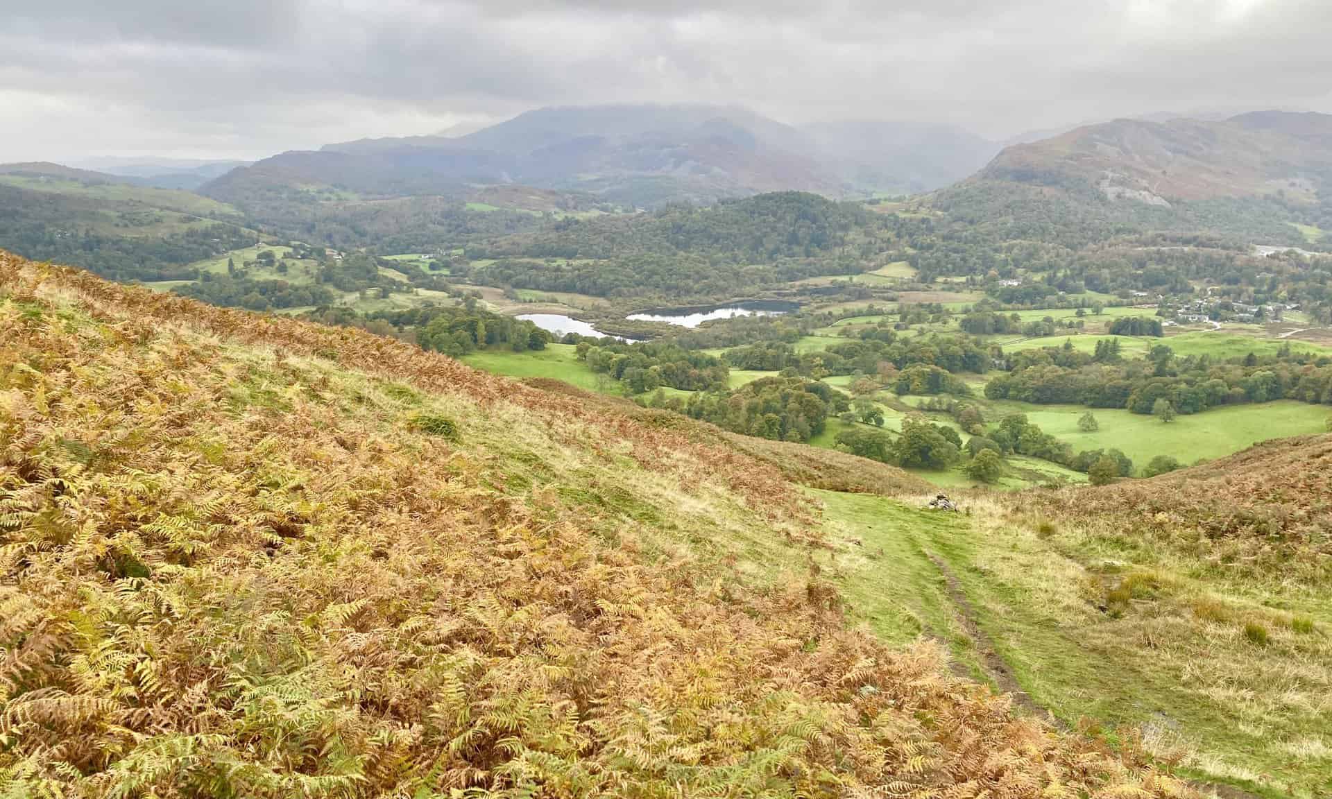 The view south-west towards Elter Water from Loughrigg Fell's Lad Crag. Lingmoor Fell is to the right of the lake and Wetherlam is in the background.