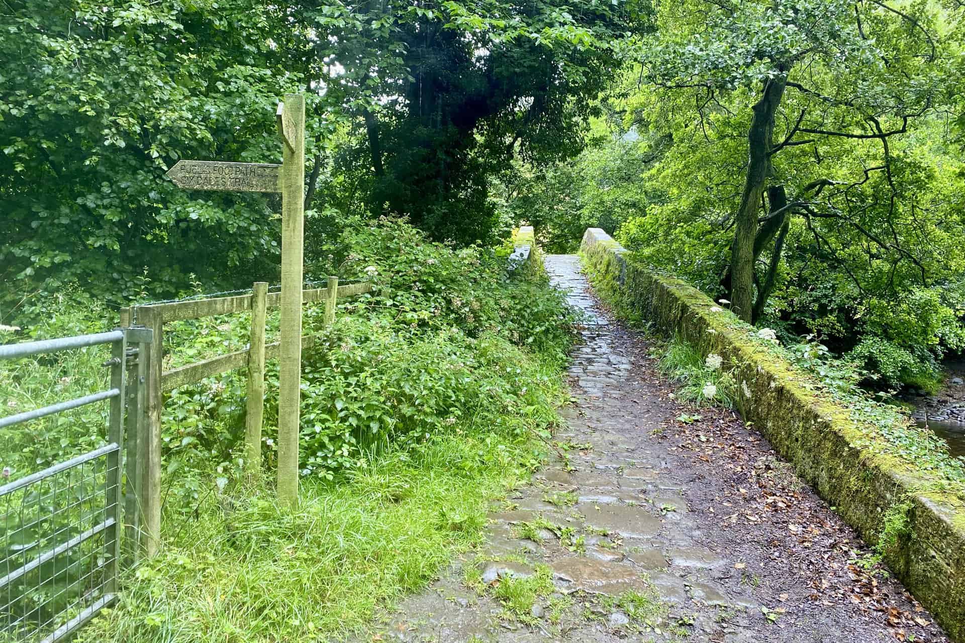 Dobpark Bridge over the River Washburn, with an accompanying signpost for the Six Dales Trail leading back to Swinsty Reservoir.