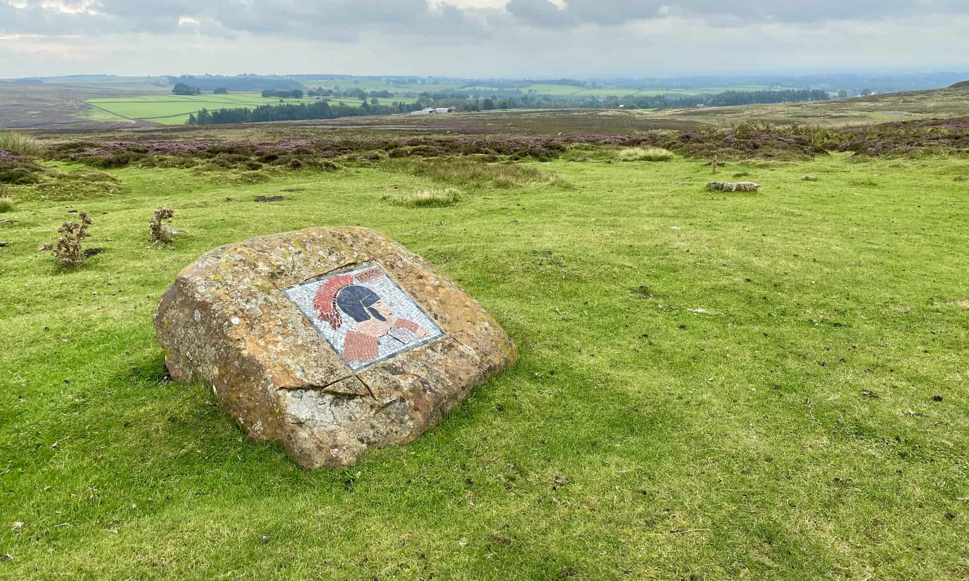 The Roman Soldier mosaic with Kirkby Malzeard Moor in the background. The halfway point of this Nidderdale walk.