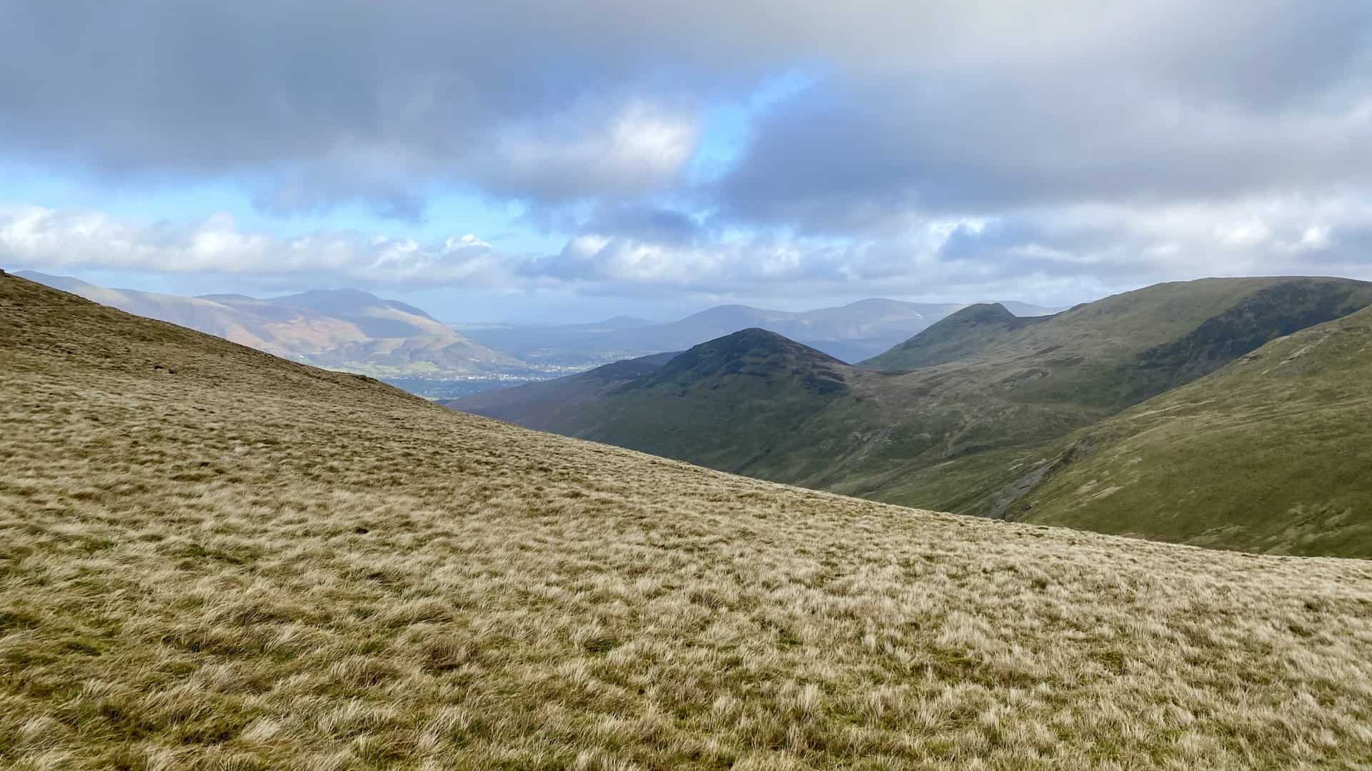 The view from Sand Hill, about halfway around this Grisedale Pike walk. The sun shines down on Keswick and the Blencathra range of mountains.