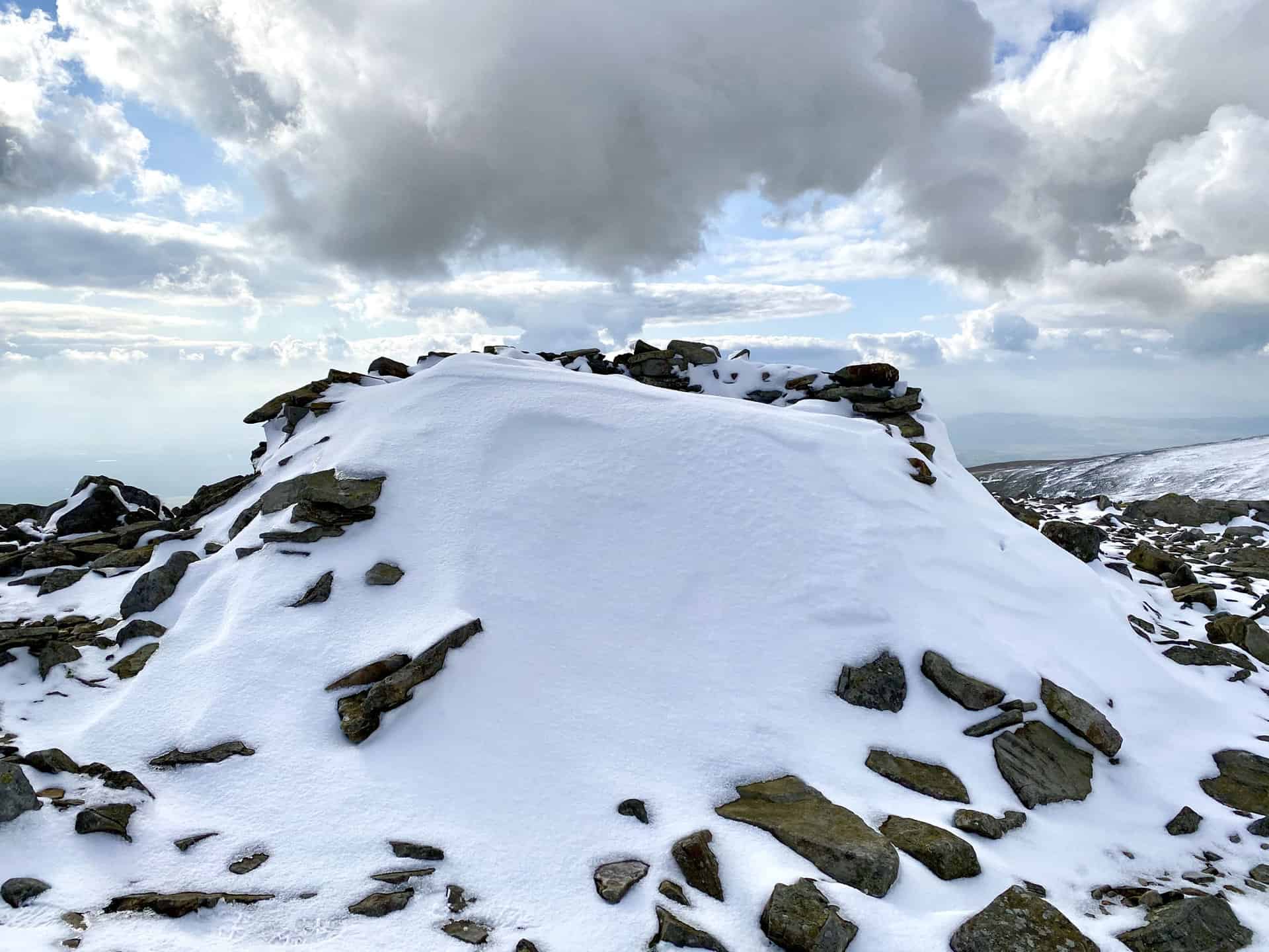 Shelter on the summit of Little Dun Fell filled with snow.