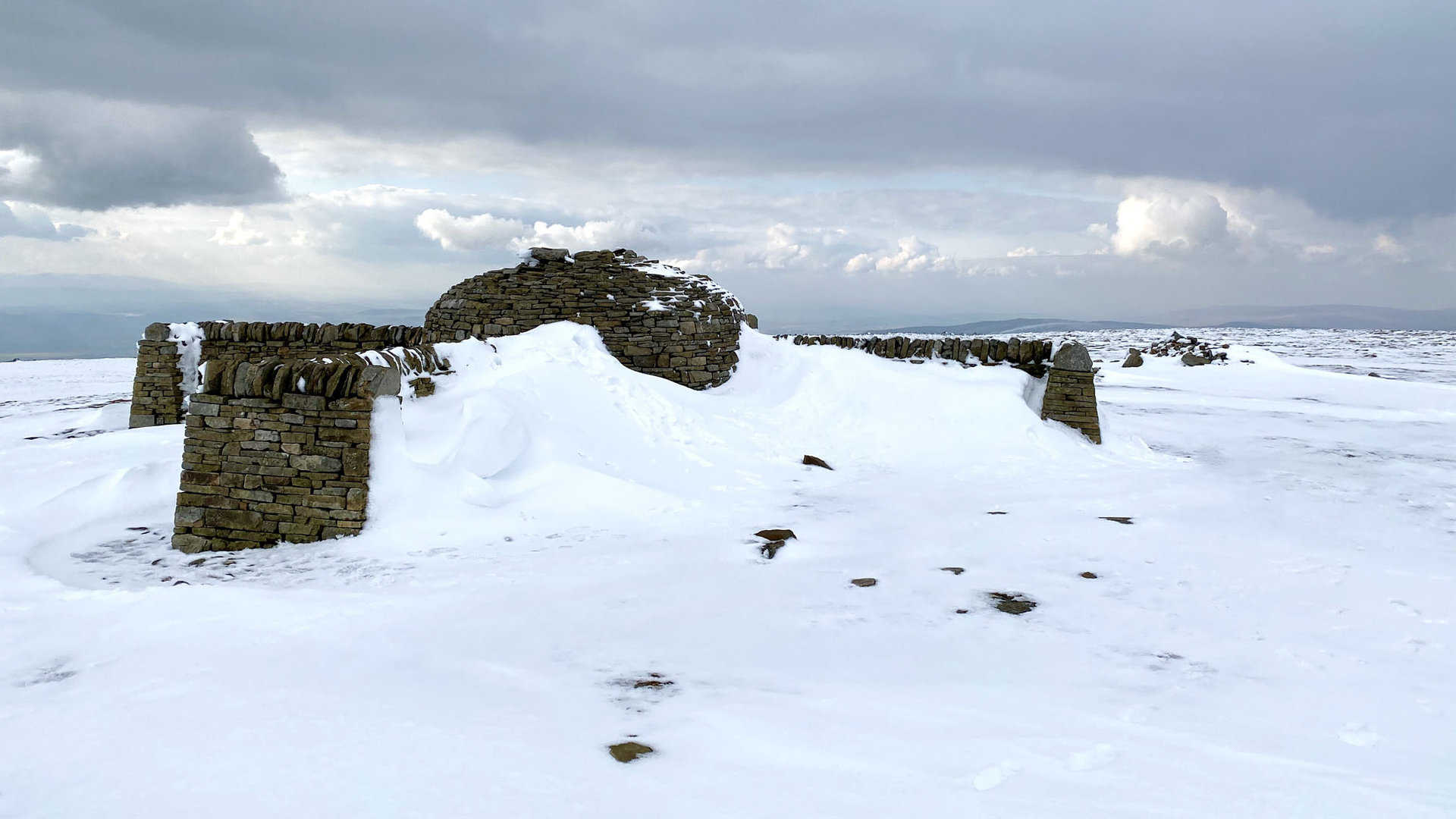 Shelter and seating area on Cross Fell completely filled with snow. This is the halfway point of this Cross Fell walk.