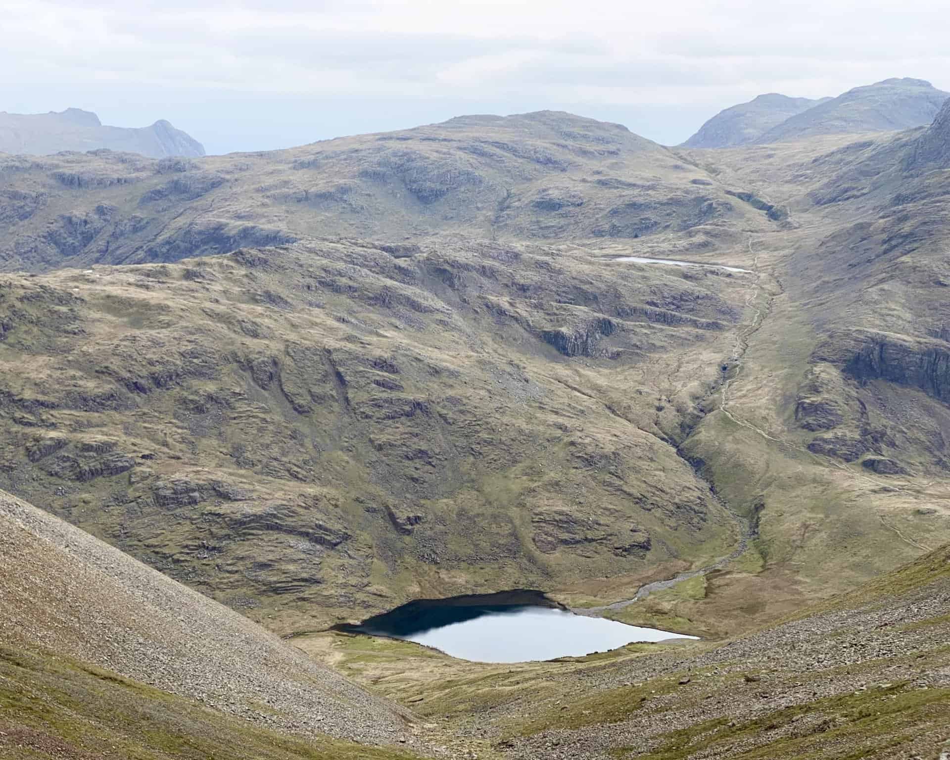 Another view of Styhead Tarn and Sprinkling Tarn. To the far left of the picture on the horizon are the knobbly peaks of Pike of Stickle and Harrison Stickle in the Langdale Fells.
