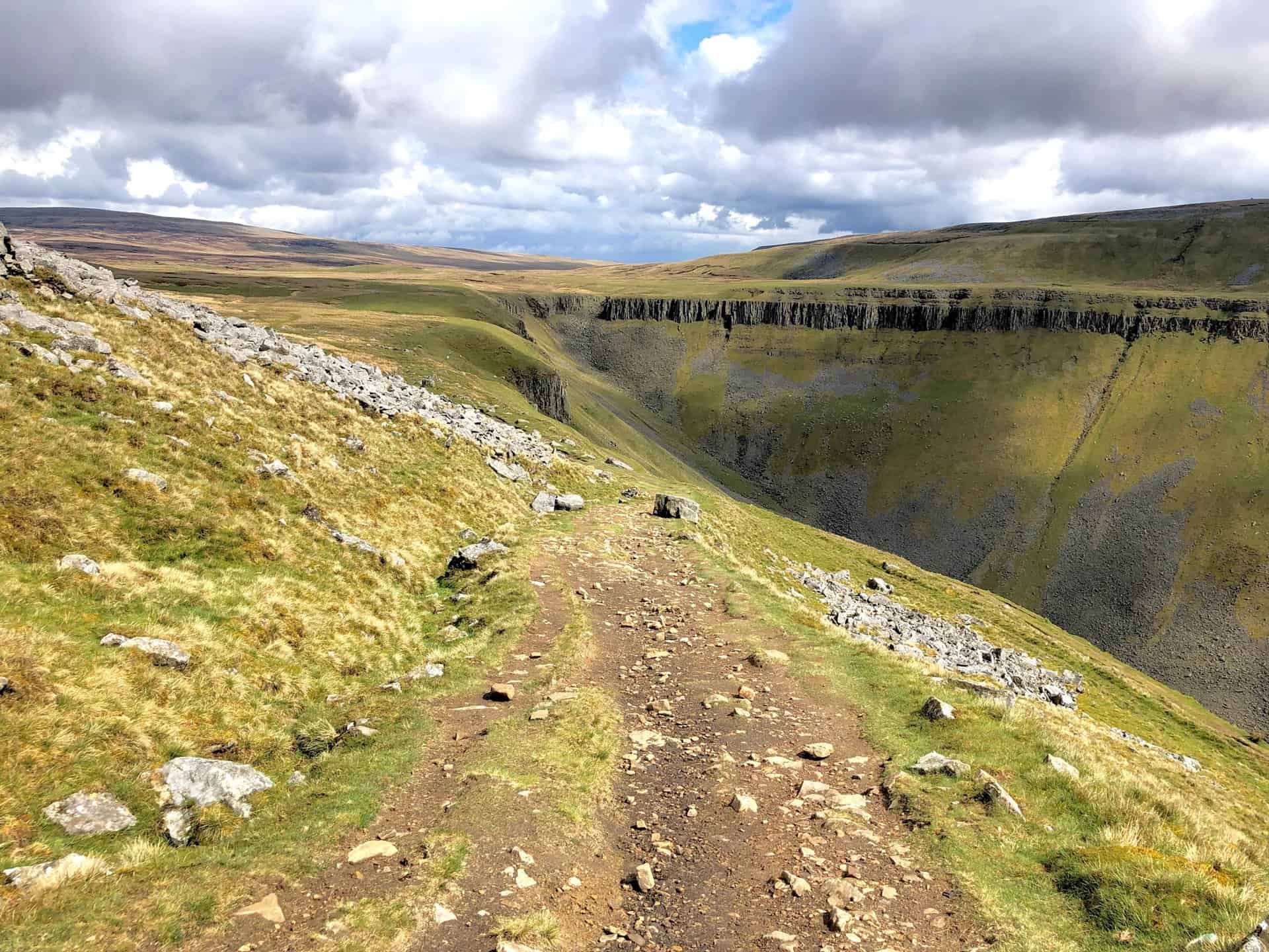 High Cup Nick, at the valley's head, becomes visible from the Pennine Way; the prominent rocky feature is High Cup Scar. Reaching this point is a rewarding moment, marking a significant achievement on the High Cup Nick walk.
