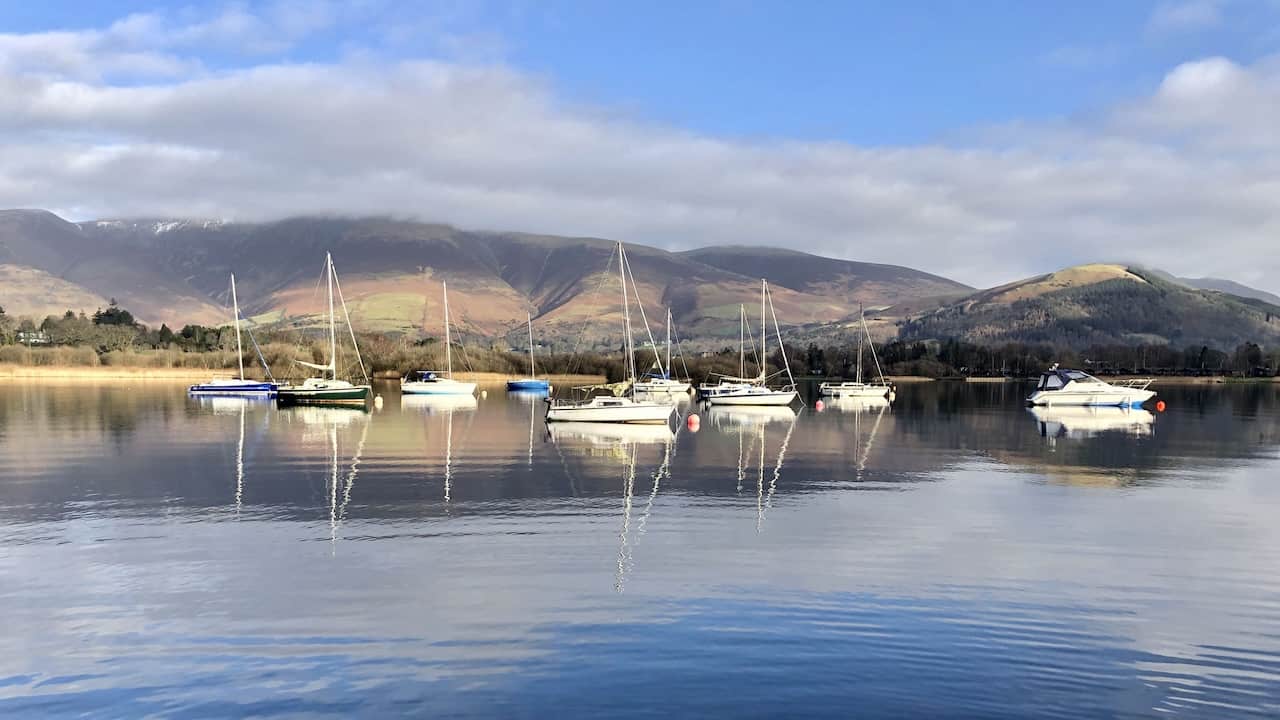 Looking north-east across Derwent Water towards Keswick, with the Blencathra range of mountains in the far background, left of centre. This panoramic view is a quintessential part of the Derwent Water circular walk, offering a comprehensive experience of the Lake District's majestic beauty.