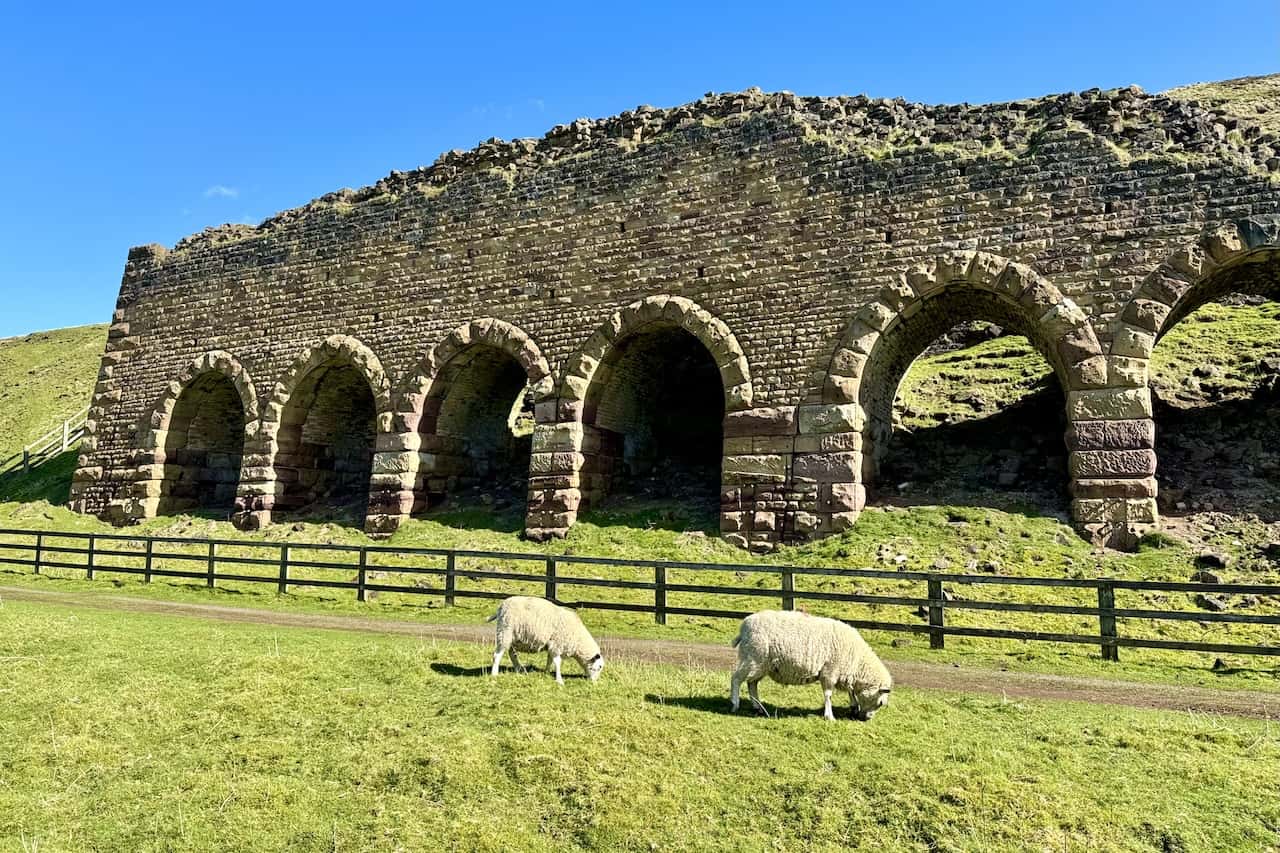 The Stone Kilns, similar in purpose to the Iron Kilns, were utilised to process the ironstone. Known as ‘calcining’, this roasting process began around 1863 for Rosedale’s East Mines. Before being transported to blast furnaces, ironstone was roasted in these substantial kilns to remove impurities, enrich the iron content, and break down large lumps into a smeltable size. This procedure, which also involved discarding waste, was instrumental in reducing transportation costs.
