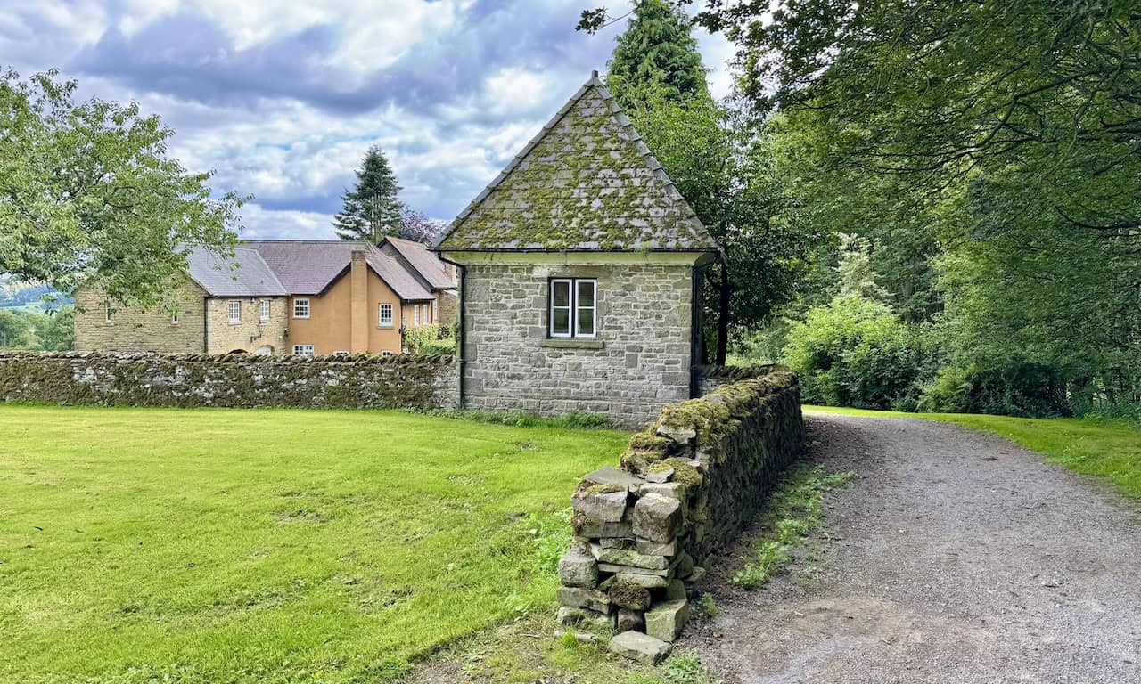 A mossy-roofed building stands near Fern Gill House within the Tupgill estate grounds.
