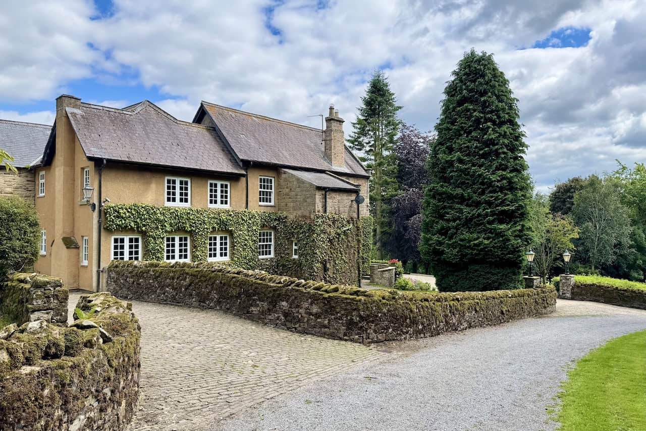 Fern Gill House is a stone and rendered property framed by hedges and conifers. This is about halfway around the Tupgill Park walk.
