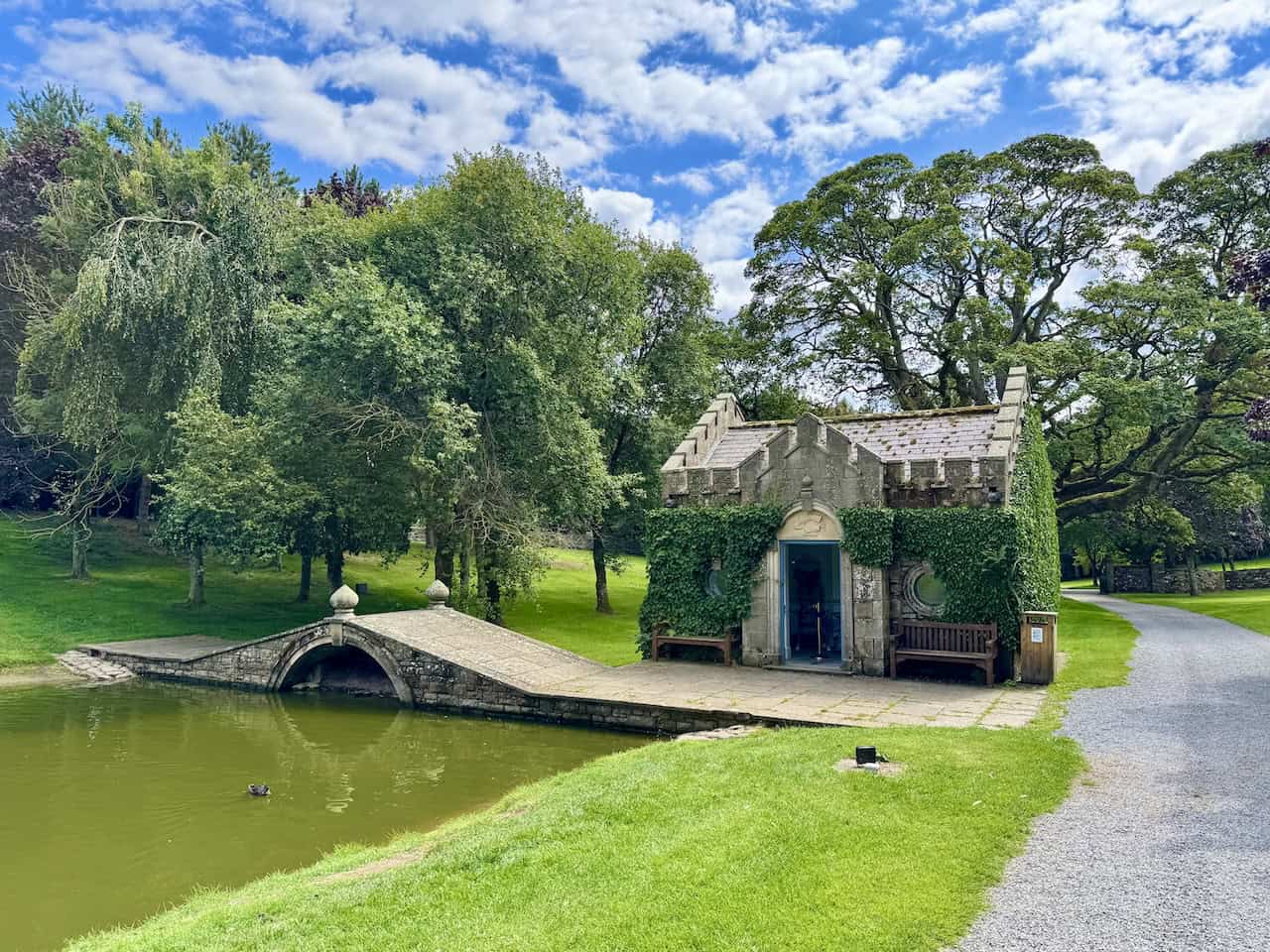 The Fishing Temple is a peaceful, ivy-covered structure beside a quiet pond.
