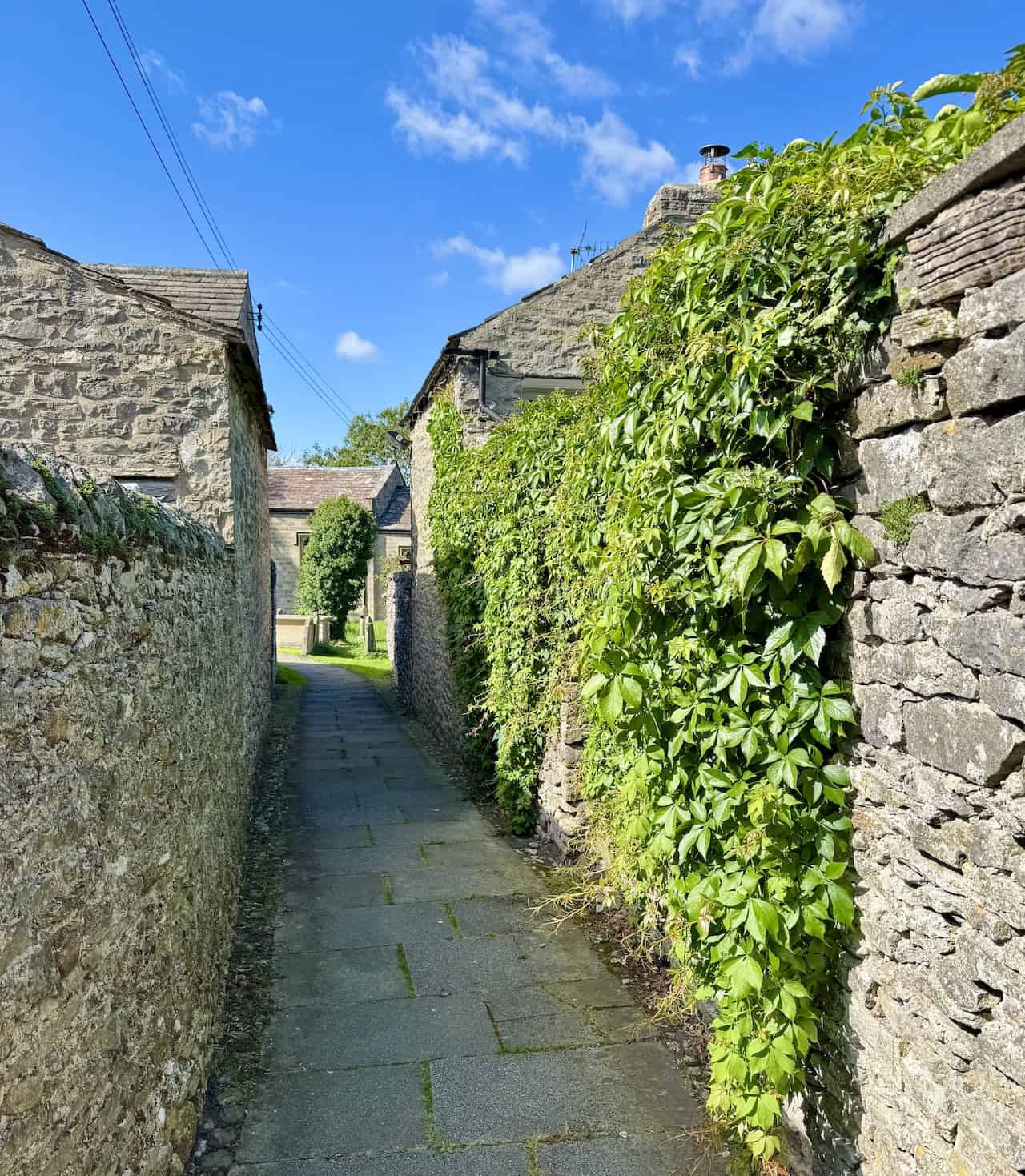 A narrow alley lined with ivy leads to West Witton’s churchyard.
