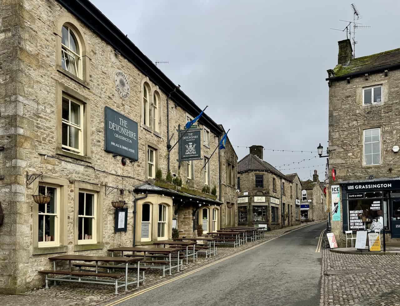 A walker passing the Devonshire Arms in Grassington, a pub that has featured in the television series All Creatures Great and Small on this Grassington circular walk.