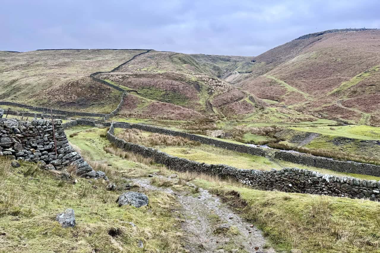 The path descending towards Hebden Beck on the Grassington circular walk, with the limestone pastures of Wharfedale spread out below.