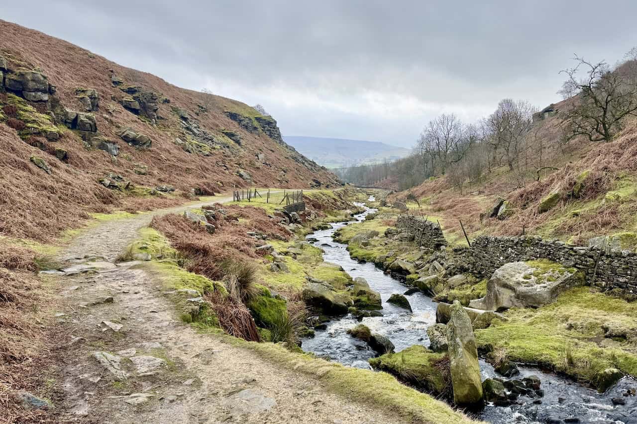 A view along Hebden Beck as the path continues through the peaceful valley, with remnants of the mining industry visible on the slopes above on the Grassington circular walk.