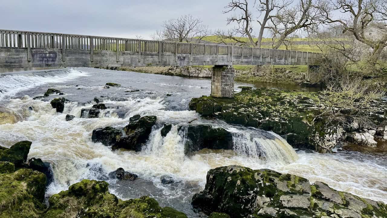 Linton Falls in full flow on the River Wharfe near Grassington, where a natural limestone waterfall and a pair of artificial weirs create a spectacular scene on the Grassington circular walk.