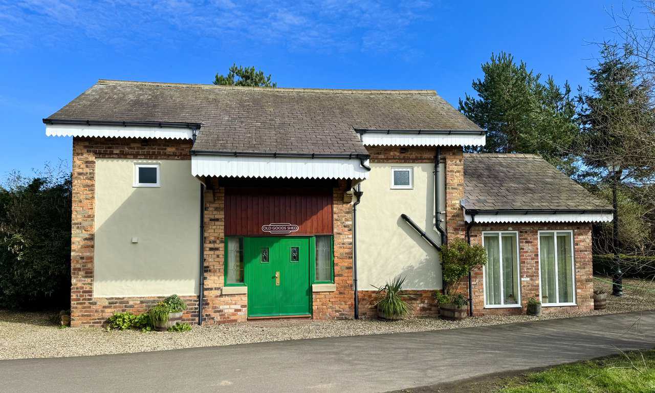 Oscar, the restored 1962 Mark 1 railway carriage at Cloughton Station, painted deep red and standing on the original track bed between the platforms.