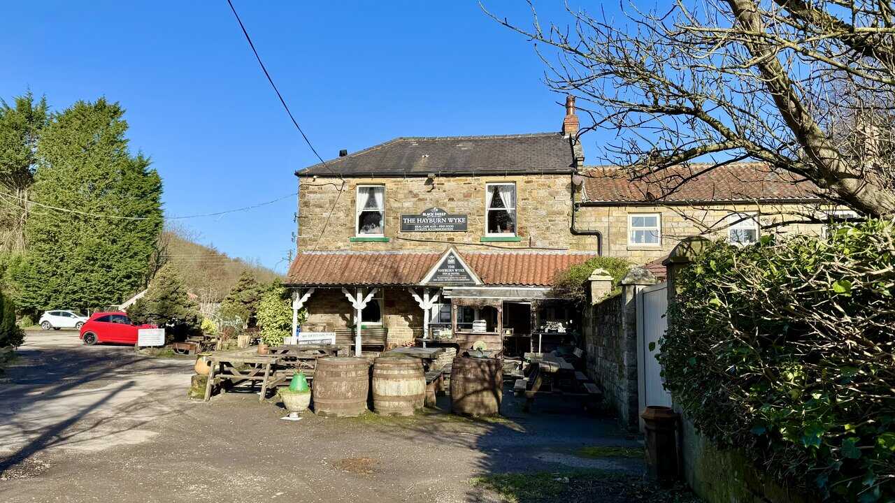 Hayburn Wyke Hotel, a stone-built country pub with outdoor benches and wooden barrels at the front.