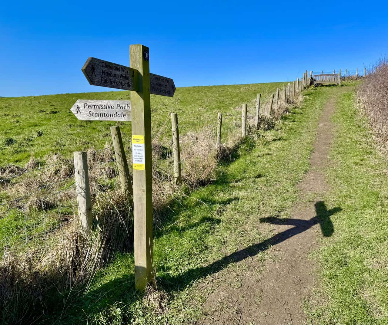 Wooden signpost and bench at Petard Point overlooking the North Sea from the Cleveland Way.