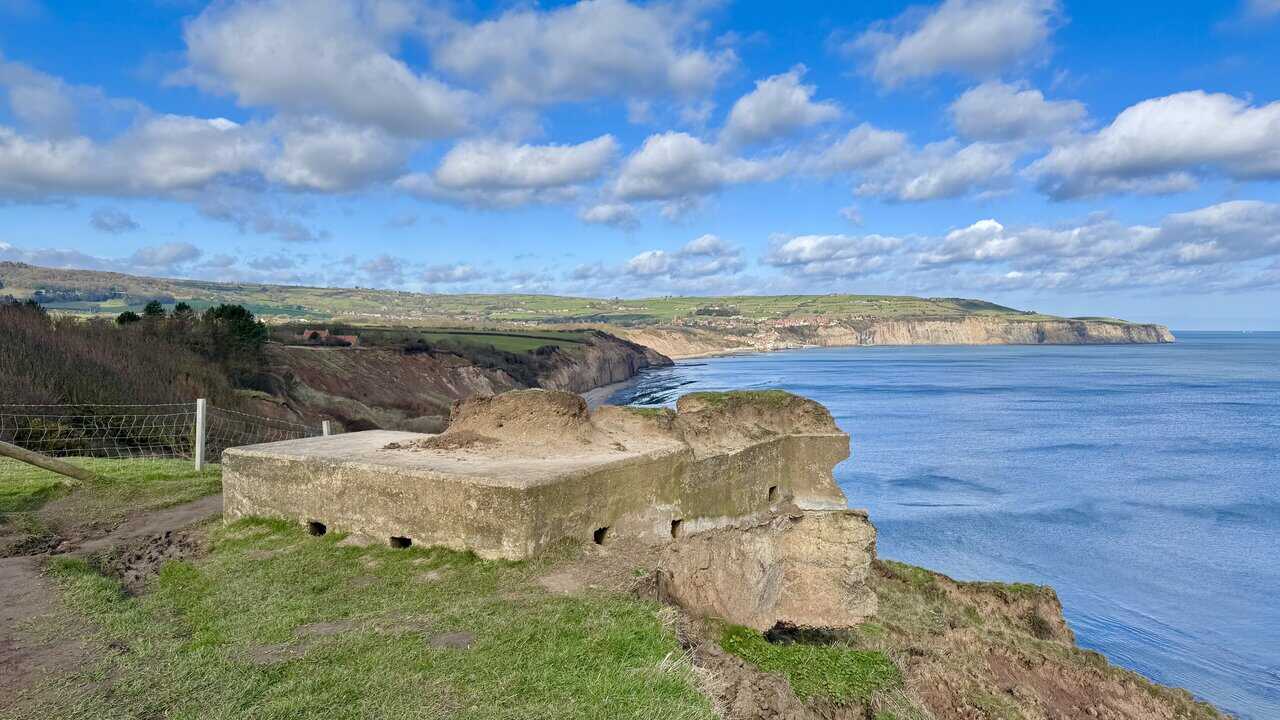 Second World War pillbox on the cliff edge at Peter White Cliff, partly crumbling above the wide bay. This is about one quarter of the way round the Ravenscar walk.