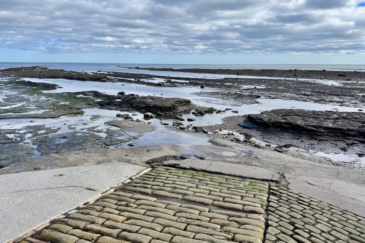 Robin Hood’s Bay beach at low tide, with a wide wave-cut rock platform and an old cobbled slipway leading to the shore.