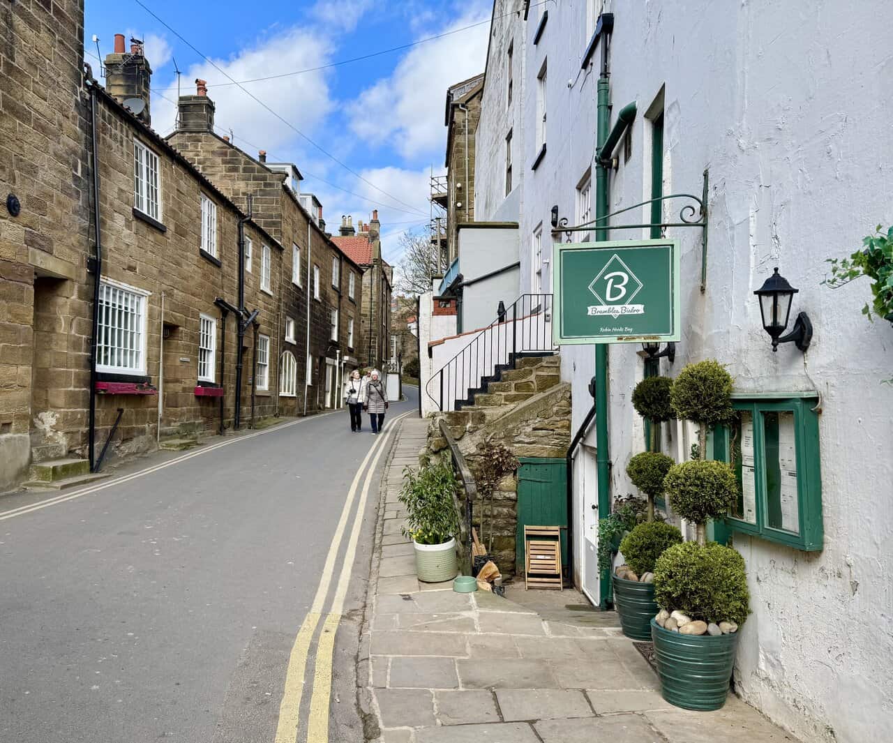 Steep main street in the lower village of Robin Hood’s Bay, lined with stone and whitewashed cottages climbing the hillside.