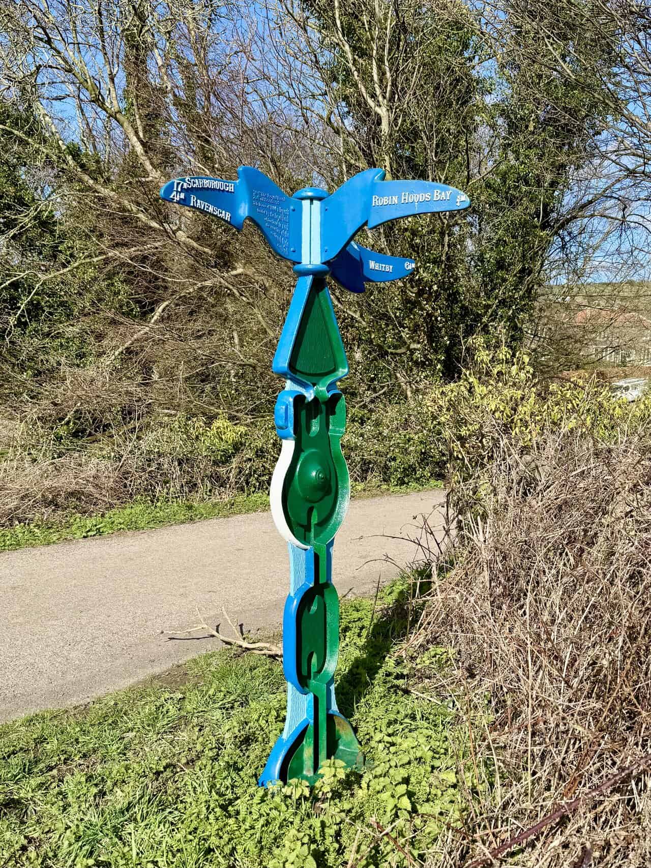 Blue and green Cinder Track signpost on Thorpe Lane, pointing towards Ravenscar and Scarborough along the old railway route. This is about halfway round the Ravenscar walk.