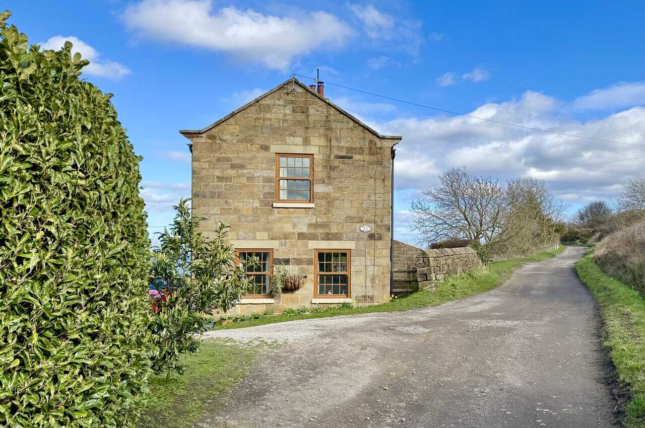 Ewefield House beside the Cinder Track, a neat stone cottage with timber-framed windows.