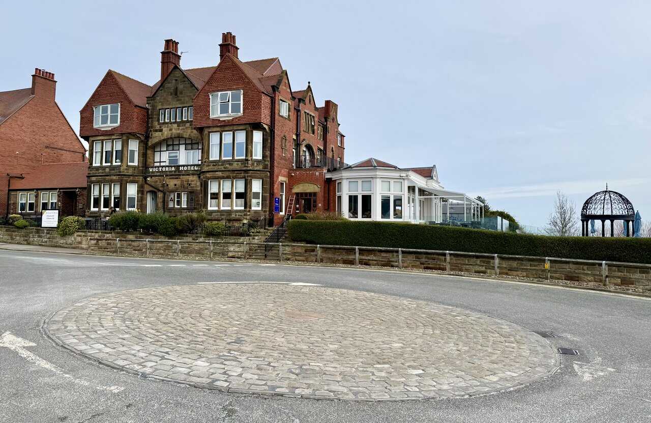 Victoria Hotel with red-brick frontage and iron gazebo overlooking Robin Hood’s Bay.