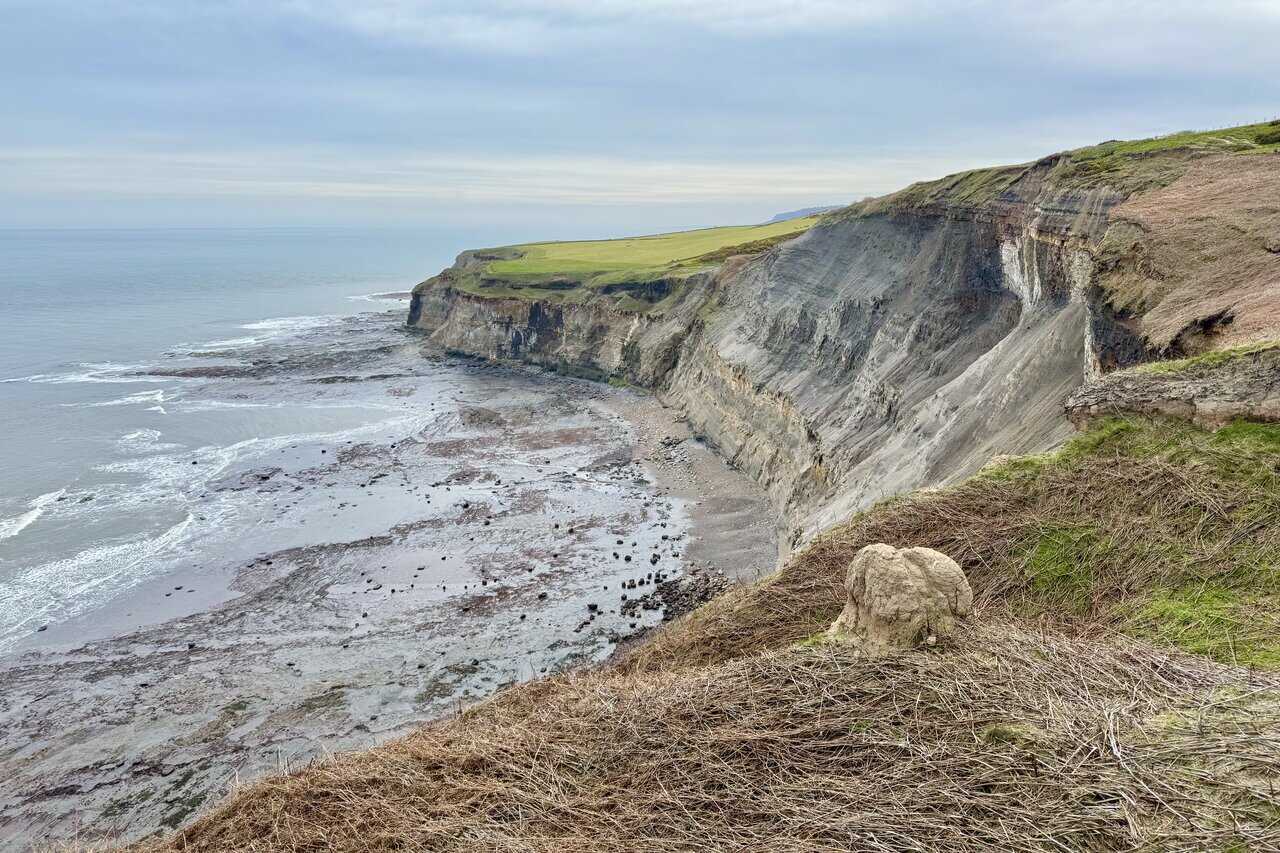 Dramatic cliff layers and boulder-strewn shore seen from Normanby Stye Batts.