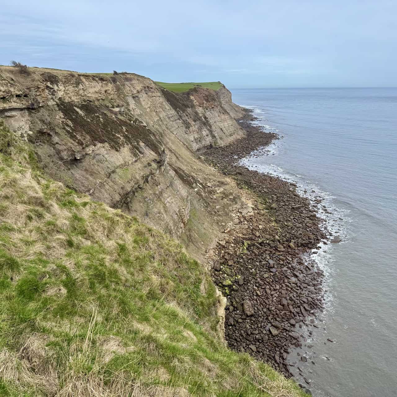 Final northward view along layered cliffs before the route turns inland.