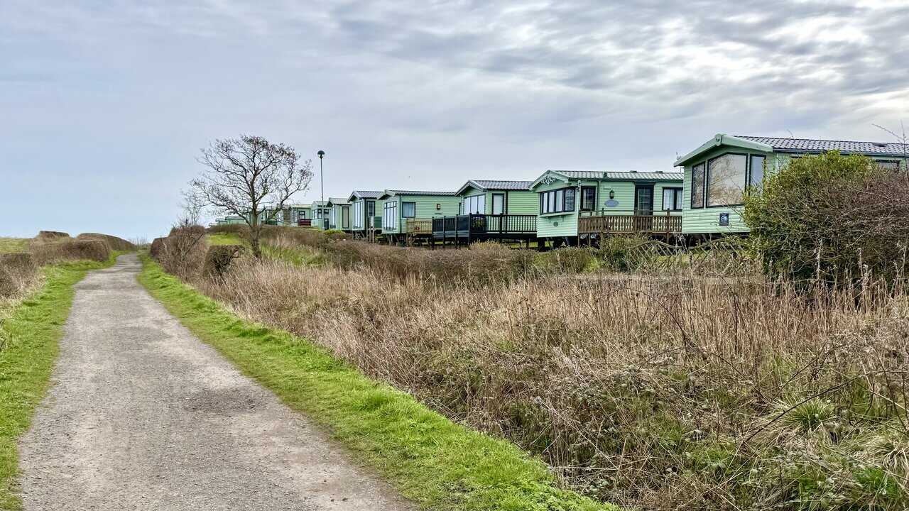 Green static caravans beside the Cinder Track on the return leg to the village.