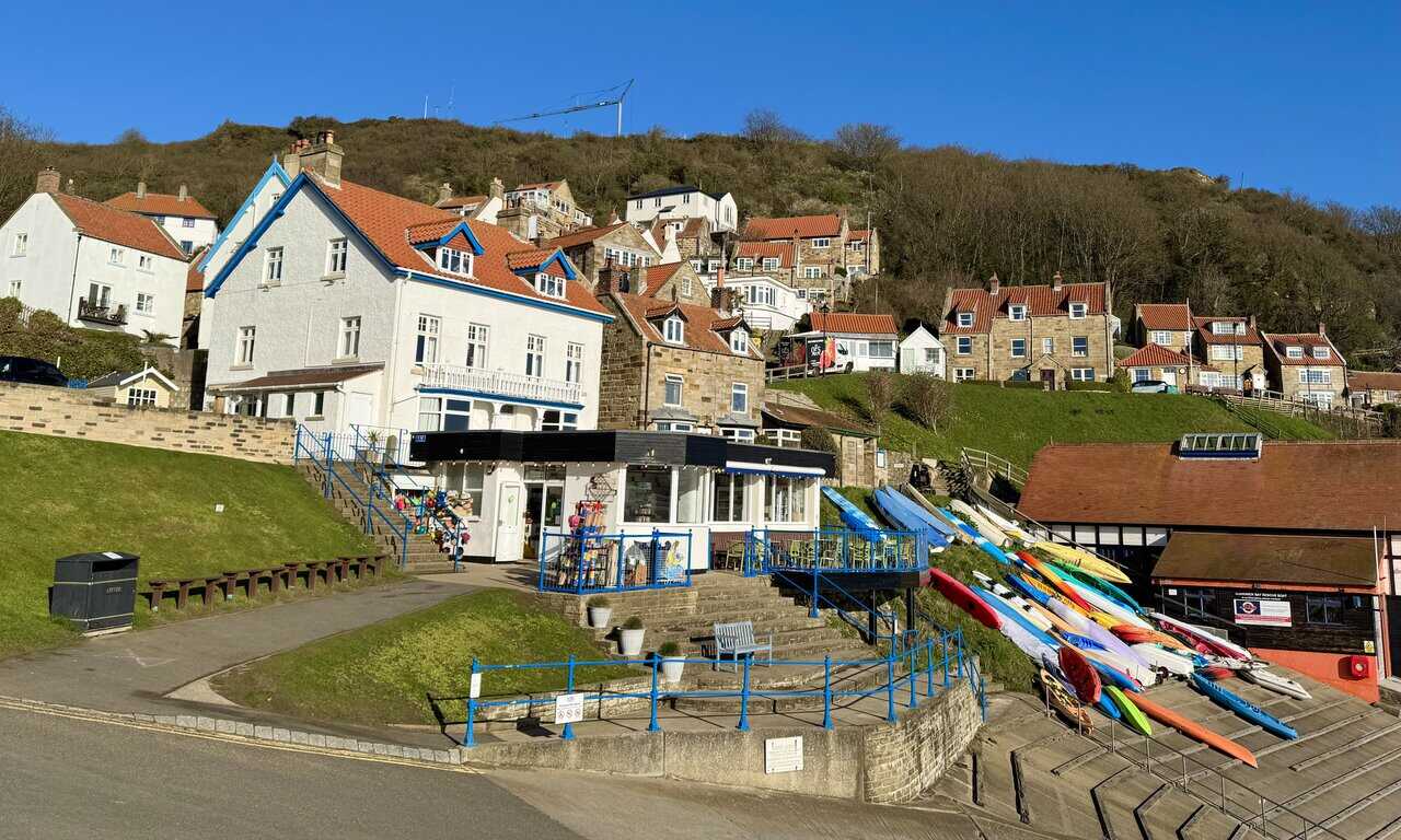 Lower Runswick village seen from the steep approach road, with tightly packed cottages, red pantile roofs, narrow paths and steps descending towards the sandy bay.