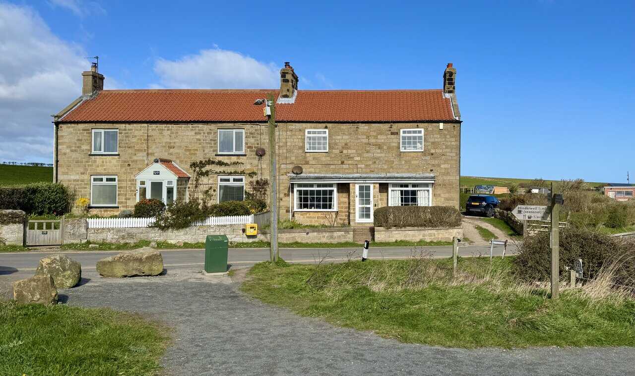 Sandstone houses with red pantile roofs in Port Mulgrave, once built for the mining community, lining the roadside.