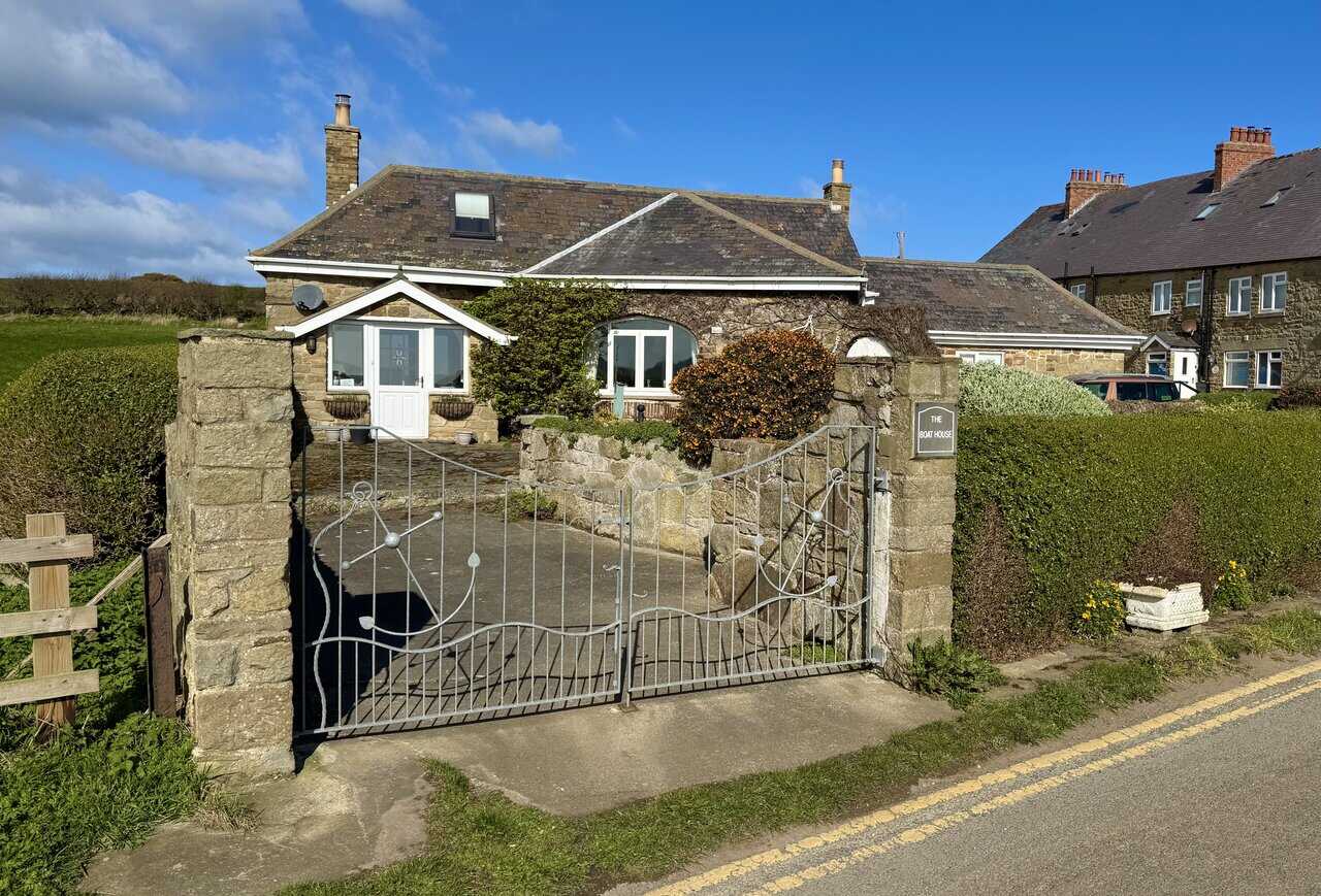 The Boat House on the Runswick Bay walk at Port Mulgrave, a stone-built bungalow with iron gates and sandstone pillars near the quiet former mining site.