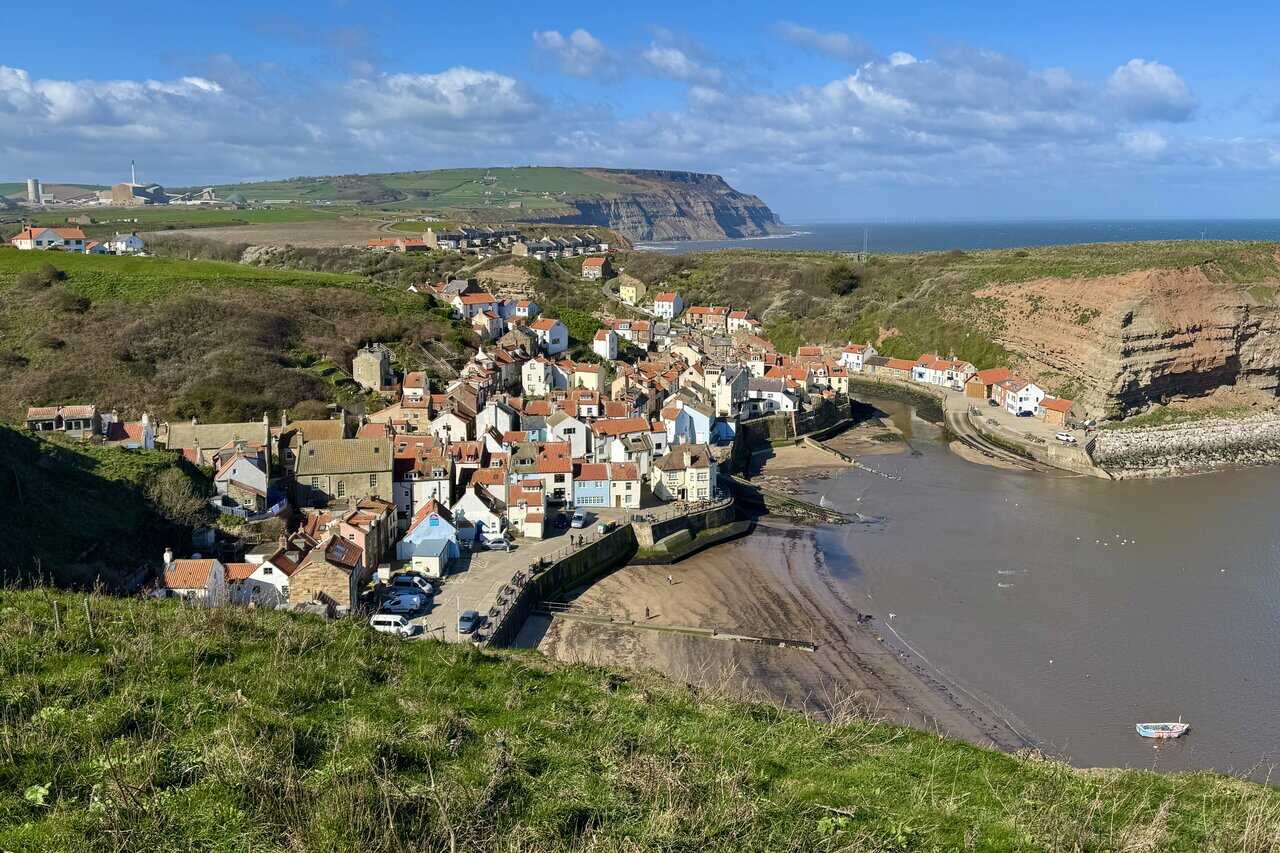 Looking down into Staithes, with clustered cottages above the harbour, Cowbar Nab beyond, and Boulby Cliffs stretching into the distance.