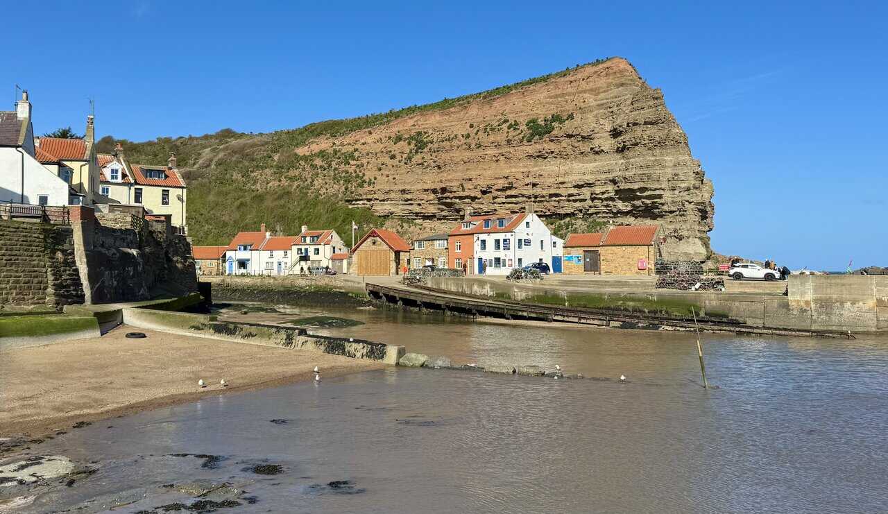 The Cod and Lobster pub at Staithes harbour, flanked by weathered cottages and backed by the dramatic cliff of Cowbar Nab.