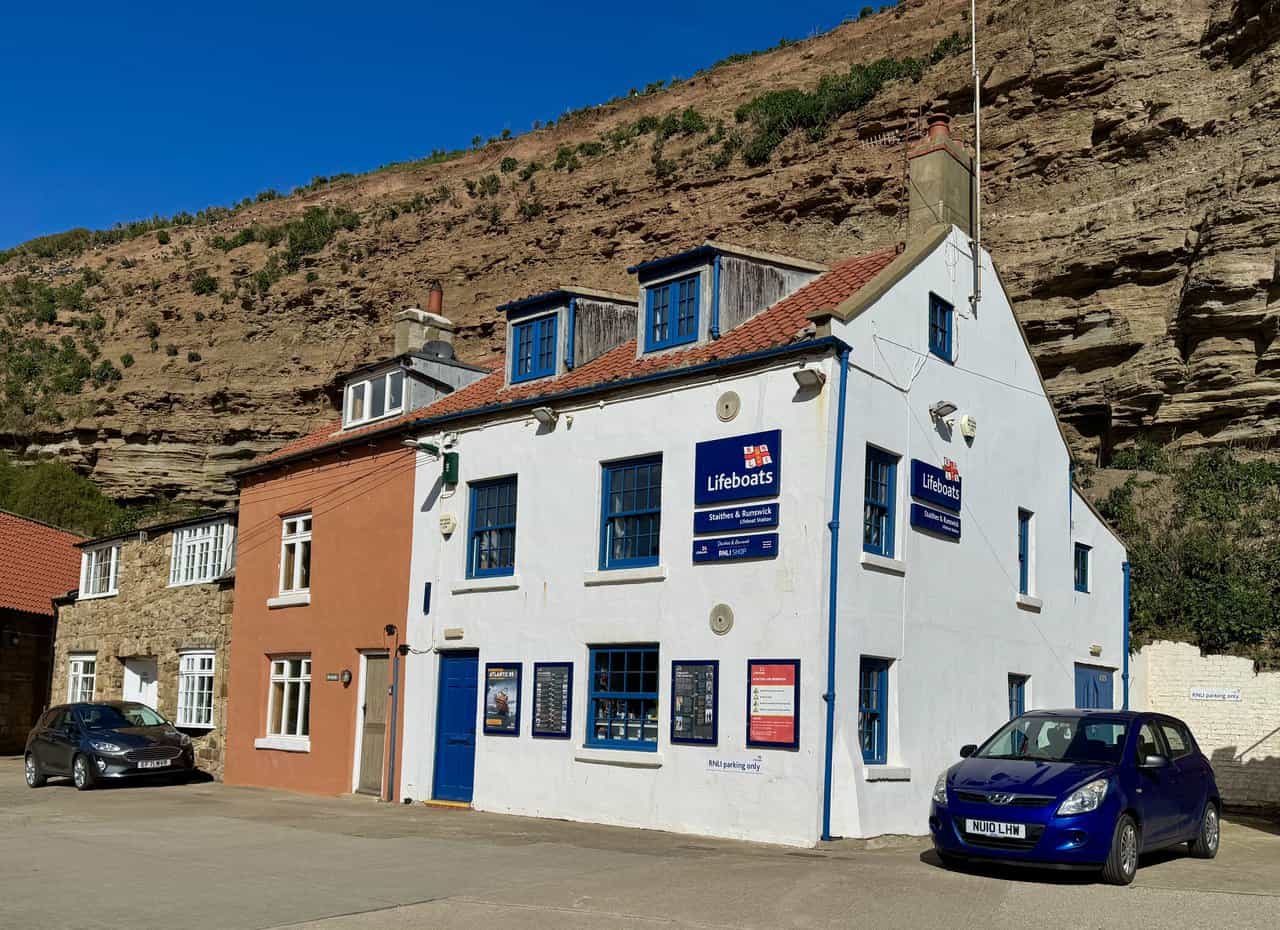 Staithes and Runswick Lifeboat Station on the on the Runswick Bay walk, with white walls, blue trim and the quayside in front.