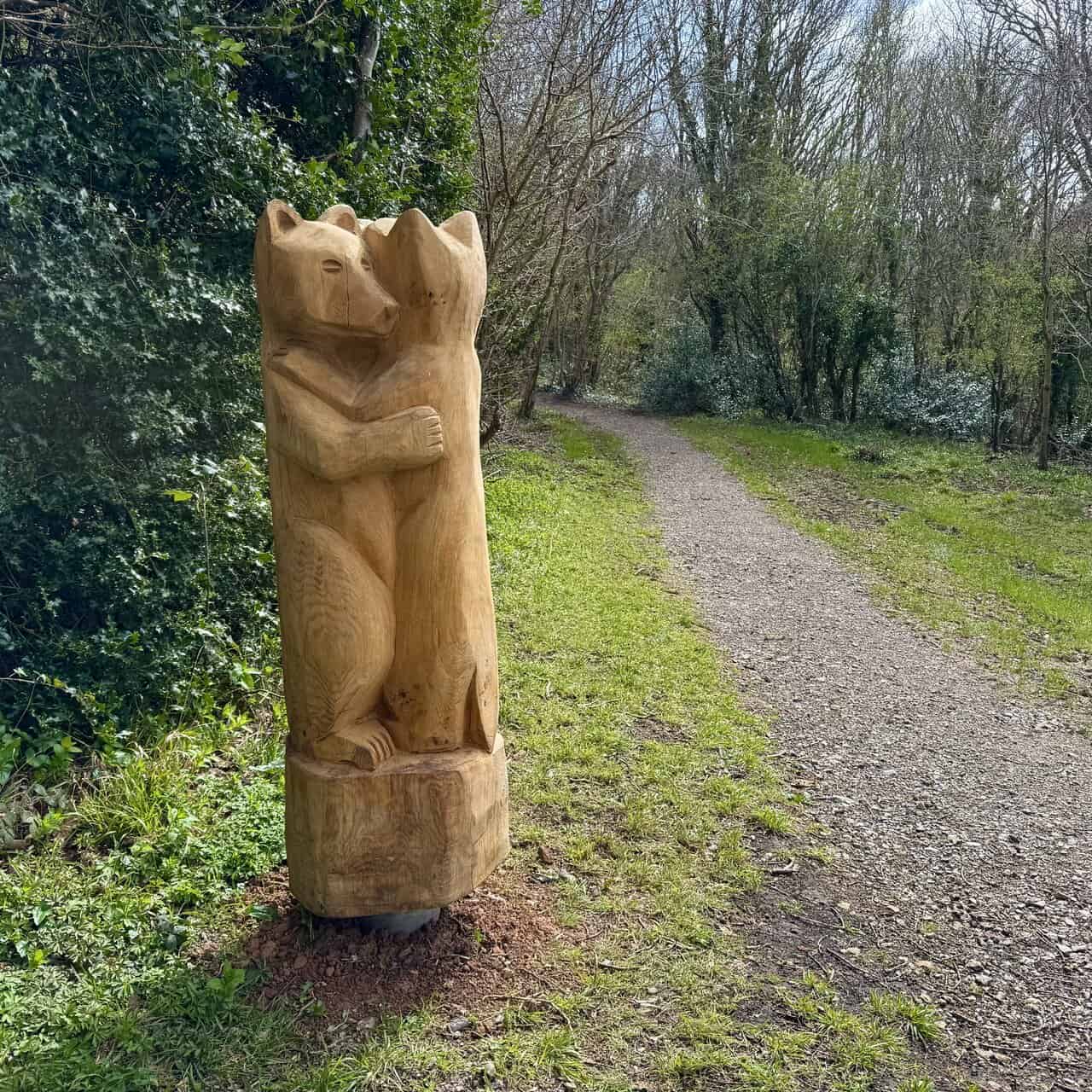 Two bears on the Runswick Bay walk carved from a single tree trunk beside the path in Oakrigg Wood, surrounded by quiet woodland.