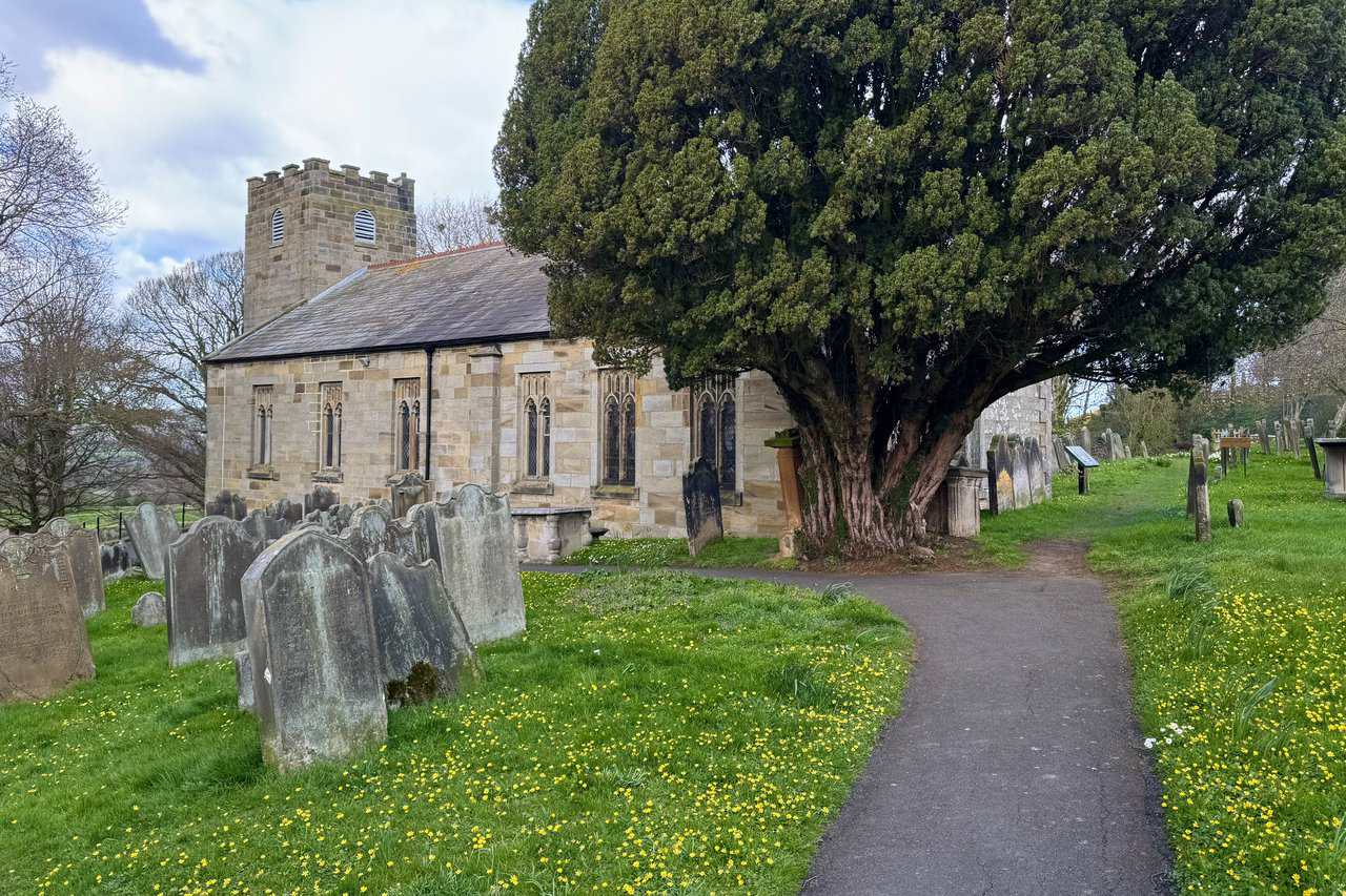St Hilda’s Church in Hinderwell, set among old headstones, wildflowers and a large yew tree in the churchyard.