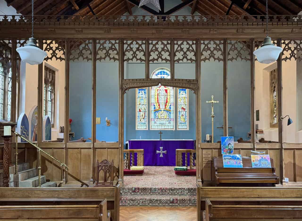 Close view of the carved wooden rood screen inside St Hilda’s Church, showing arched openings and gothic detail.