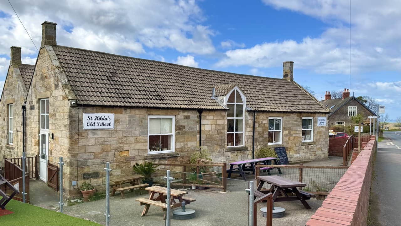 St Hilda’s Old School in Hinderwell, a single-storey sandstone building with picnic benches outside in the former school yard.