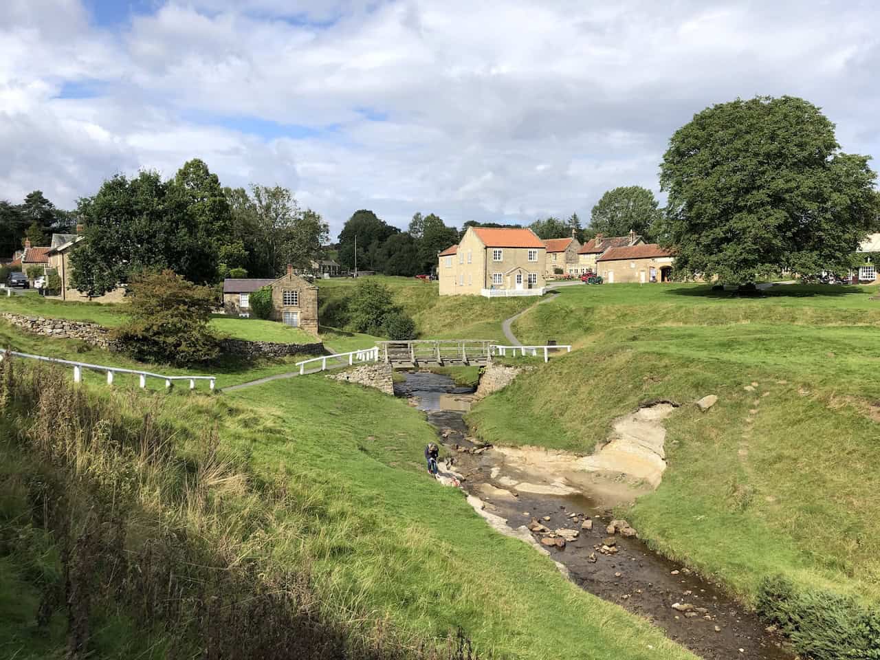 The tranquil village centre of Hutton-le-Hole in the North York Moors National Park, with sheep grazing on the common beside Hutton Beck, just a short walk from Ryedale Folk Museum.