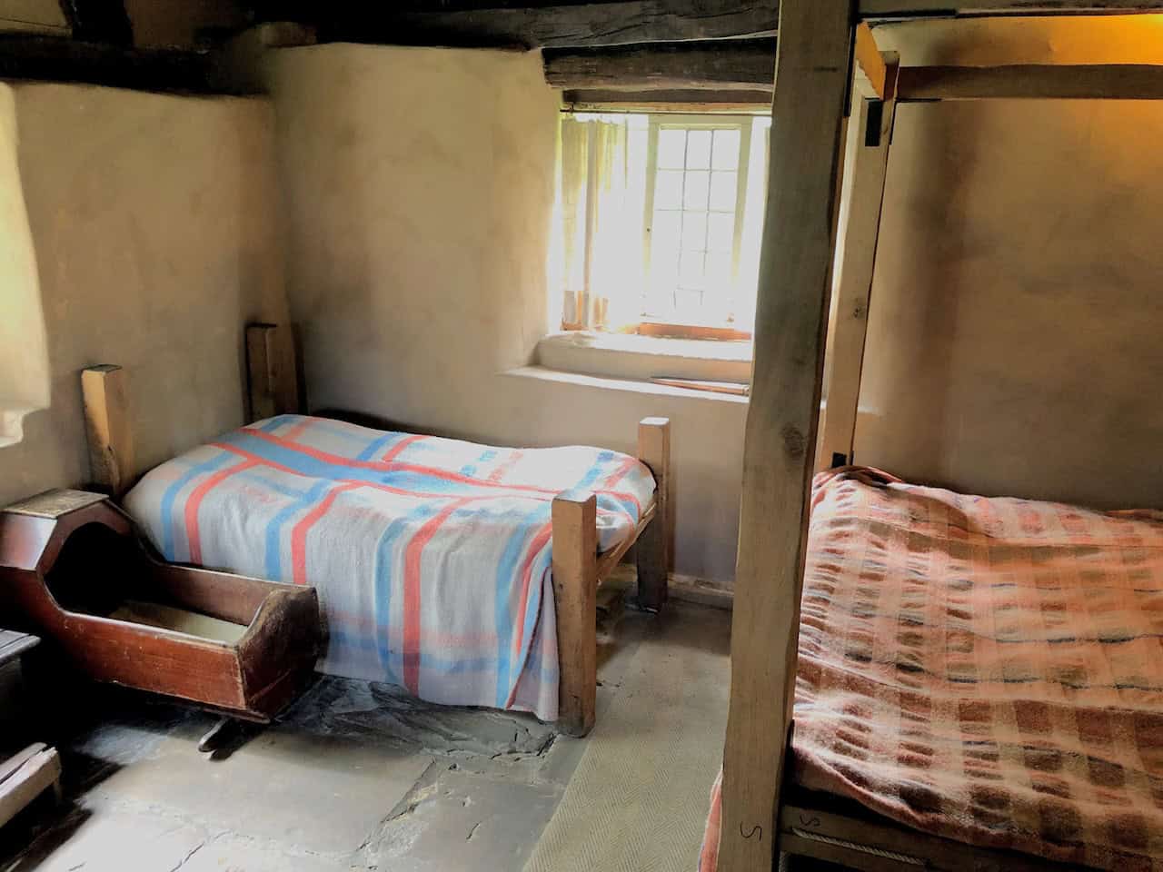 The interior of Stang End Cruck House, giving visitors an authentic glimpse into the domestic life of a 17th-century yeoman farmer, with the original witch post standing beside the hearth.