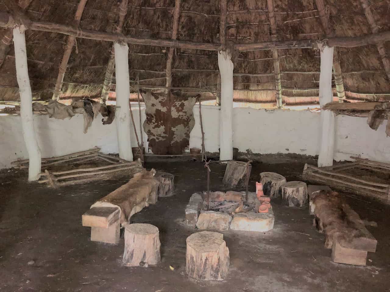 Inside the Iron Age Roundhouse, where extended families once lived communally in a single circular room, gathered around a central open fire with smoke escaping directly through the thatch above.