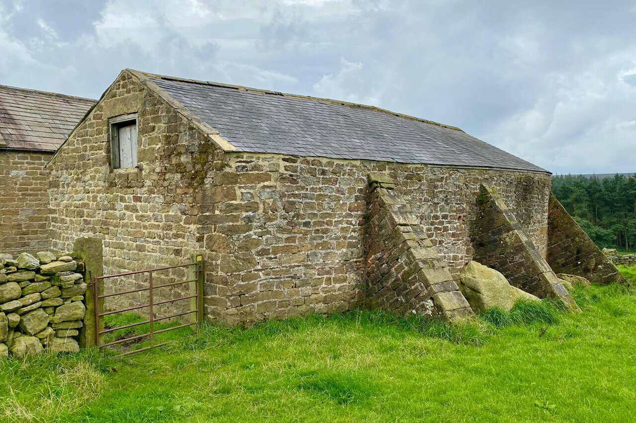 A distinctive buttressed barn beside the route near Bents House.