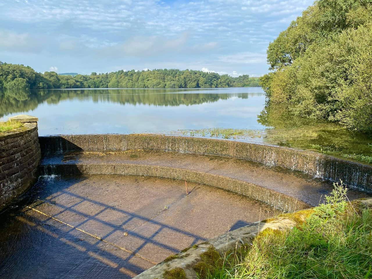 The stone water outlet at Lumley Moor Reservoir beside the peaceful water.