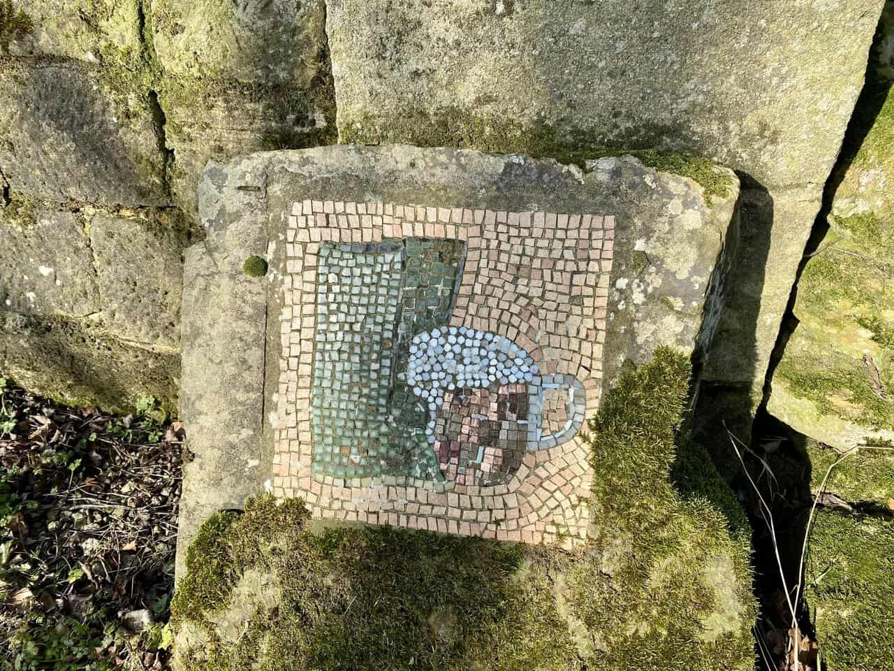 The Boots and Beer mosaic adds a playful touch beside the main road through Dallowgill.