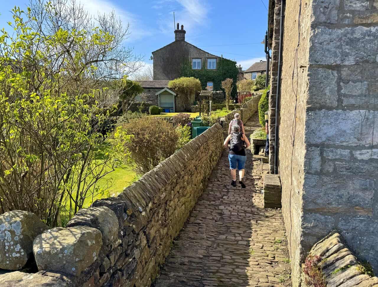 Walking along the narrow path in front of the houses overlooking Gayle Beck in the village of Gayle.